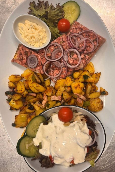 Verschiedene Salate mit Gemüse, einer Tomate, Zwiebeln und einer Beilage aus Käse.